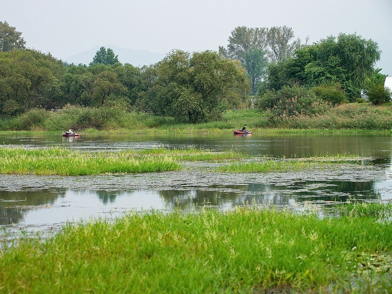 Várzea aberta com vista para serras distantes e mata ciliar